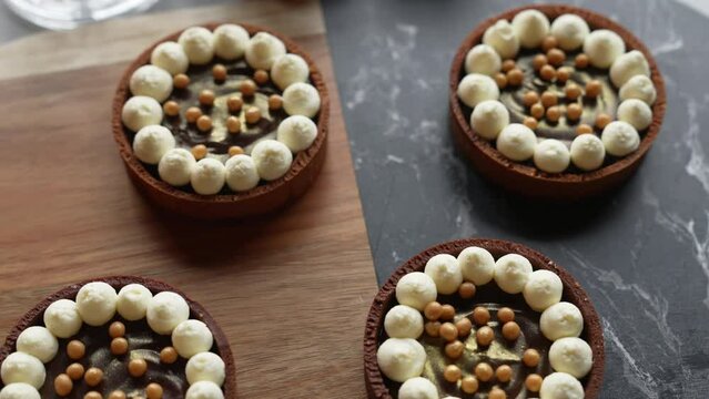 Top View Of Four Beautiful Small Chocolate Tarts Decorated With Small Meringues And Pearls. Artistic Bakery Goods. High Quality 4k Footage