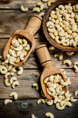 Cashews in a bowl with a wooden scoop.