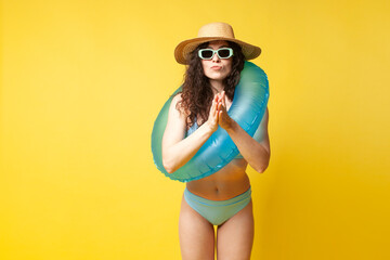 young curly slender brunette girl in a blue swimsuit in summer with an inflatable swimming ring wants to swim