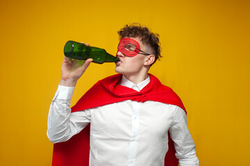 guy in a superhero costume drinks beer on a yellow background, super man drinks alcohol, the concept of drinking alcohol