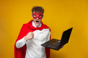 guy in a superhero costume holds a laptop and shouts on a yellow background, a superman worker...