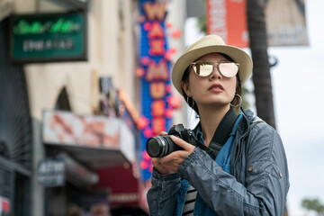Asian Female photographer is attracted by the view on the street while holding the camera