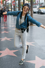 full length woman tourist joyfully opening her arms and standing on the Hollywood Boulevard.
