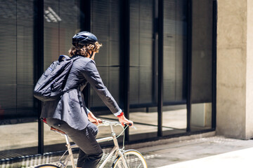 Portrait of hipster handsome businessman in suit with backpack looking forward while commuting riding bicycle on the street city way go to work.business travel transport bike concept.