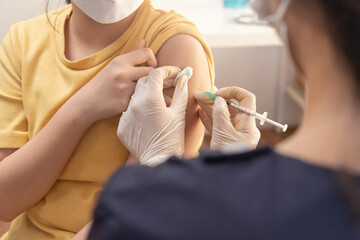 Covid-19, coronavirus asian girl kid getting vaccine from doctor, nurse giving shot to little child patient at clinic. Healthcare, immunization, disease prevention against flu or virus pandemic.