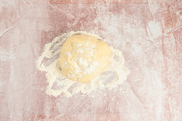 Round ball of raw bread dough and flour on a clear plastic mat, preparation for baking
