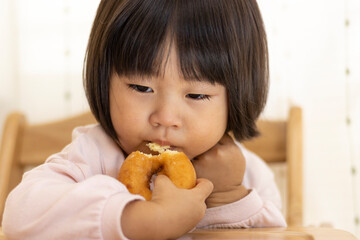 座ってドーナッツを食べる赤ちゃん（2歳4か月、女の子、日本人）