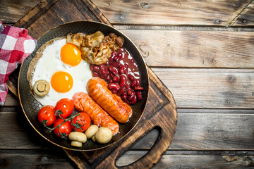English breakfast.Fried eggs with sausages, bacon and red canned beans.