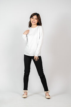 A young energetic woman wearing a white blank long sleeve shirt doing a pose