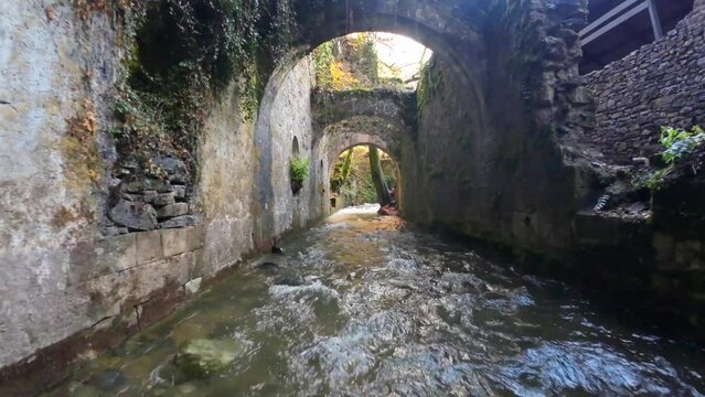 Flight of the FPV drone over a river and passing over the stone arches of an ancient ammunition factory in Eugi.