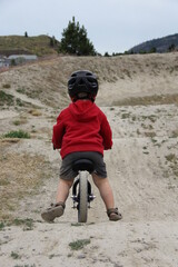 toddler boy riding balance bike in bike park