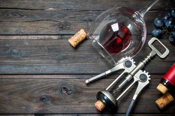 Wine background. A glass of red wine with grapes and a corkscrew .