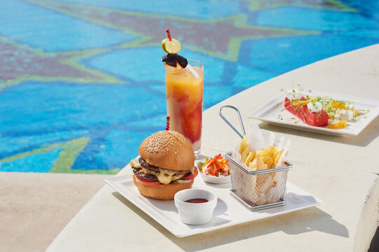 Lunch Meal On The Pool Side - Burger, Fries, Pickles, And A Cocktail