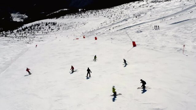 Aerial view of people skiing down a steep mountain ski slope, on a sunny winter day, in Slovakia