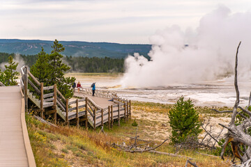 Fototapeta na wymiar Tourists watching the Clepsydra geyser on the Fountain Paint Pot Trail in Yellowstone National Park.