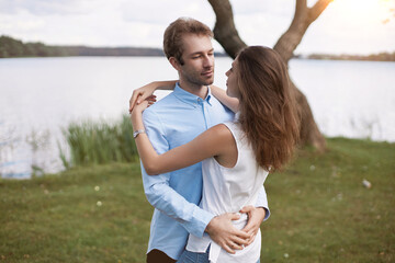 beautiful couple in love hugs standing on the river bank.