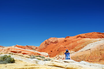 Young female hiker exploring amazing sandstone formations in Valley of Fire State Park, Nevada, USA.