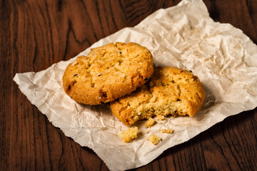 Closeup bite brown butter chocolate chip cookies on crumble paper.