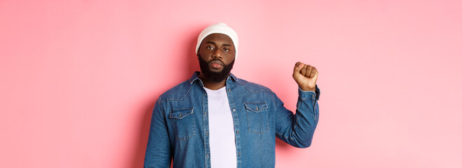 Serious and confident african-american male activist, raising fist, support Black lives matter BLM...