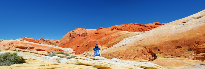 Young female hiker exploring amazing sandstone formations in Valley of Fire State Park, Nevada, USA.