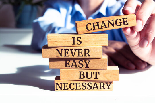 Close up on businessman holding a wooden block with "Change Is Never Easy But Necessary" message