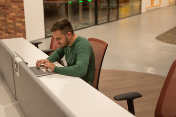 Fototapeta premium Caucasian bearded man working on laptop in modern coworking space. 