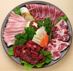 新鮮な生肉と彩り豊かな野菜を盛り合わせた焼肉盛り合わせ。牛肉、豚肉の各部位に、ピーマン、カボチャ、タマネギ、人参、椎茸、ジャガイモなどの焼き野菜を添えた一皿。焼肉店やBBQのメインメニュー、ランチや定食、スタミナ料理の販促・広告用素材に。 | Platter of assorted raw meat and vegetables for Yakiniku (Japanese BBQ).