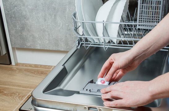 The Girl Uses The Dishwasher. The Girl Loads The Tablet Into The Dishwasher. Use Of A Dishwasher. Wash Dishes In The Dishwasher.