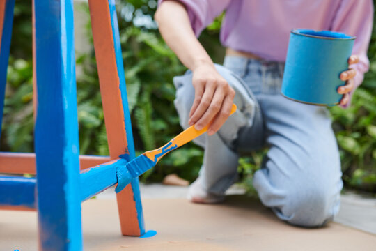 Close-up image of girl restoing old furniture in backyard