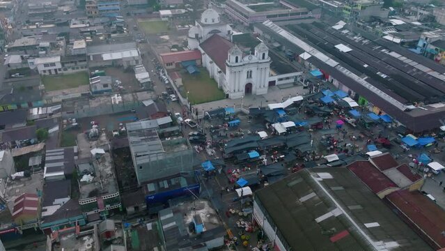 Wide slow aerial flyover around the central square in San Juan Ostuncalco, showing the market and the cathedral in the background.