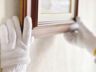 絵の額縁を持つ軍手をはめた手 © smile