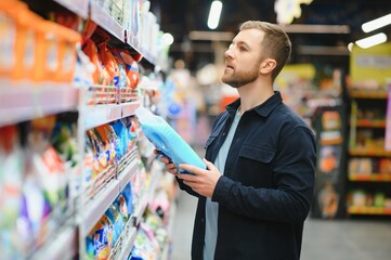 Young man in the supermarket in the household chemicals department. Large selection of products. A...