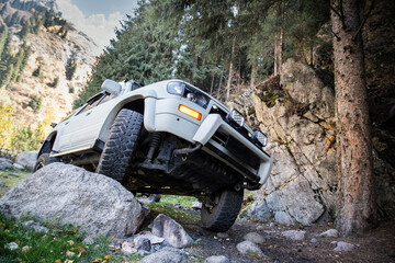 Car upgrade suspension system of a 4x4 suv. Prepared Offroader overcomes natural obstacles on a mountain road lifestyle. - obrazy, fototapety, plakaty