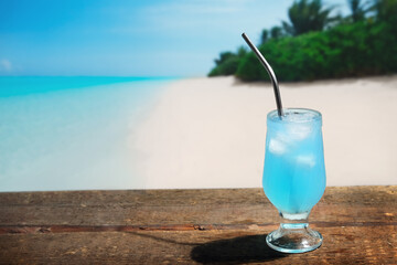 Blue lagoon alcoholic cocktail, Maldives tropical beach on background. Copy space.