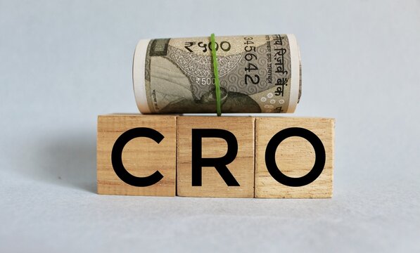 Three wooden cubes with the letters CRO on the bright surface of a white table. the inscription on the cubes is reflected from the surface of the table. CRO- short for Conversion Rate Optimization