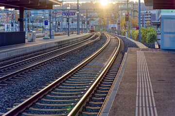 Fototapeta premium Empty platform with S-Bahn train line S6 destination Baden arriving at railway station Zürich Oerlikon in backlight on a sunny autumn evening. Photo taken November 26th, 2022, Zurich, Switzerland.
