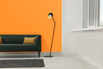 Beautiful interior with sofa and floor lamp near orange wall