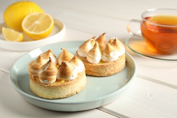 Delicious lemon meringue pies on white wooden table
