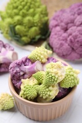 Various cauliflower cabbages on white tiled table, closeup