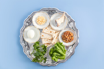 a silver plate with traditional Jewish treats for Passover. baked egg, lettuce, horseradish, bone,...