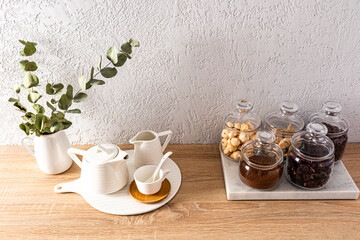 glass jars with tea, coffee, sugar on a marble board and tea items on the kitchen countertop. part of a fragment of a modern kitchen.