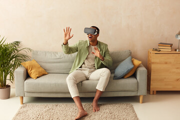 Excited Man VR Glasses. Young Guy Wearing Virtual Reality Device While Sitting On Sofa And Playing Game. New Trends Technology And Gaming concept 