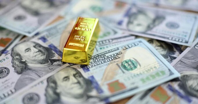 Woman hand putting gold bar on pile of dollar bills closeup 4k movie slow motion 