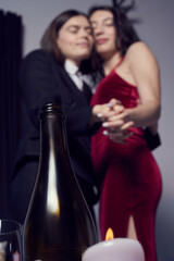 Cropped close-up shot of a two lesbian girls dancing at home. One girl wearing a black suit, another girl wearing a red dress. Happy lesbian couple enjoying a romantic moment. LGBT concept.