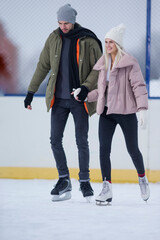 Sports and Lifestyle. Young Caucasian Couple in Winter With Ice Skates Posing Together Over a Snowy Winter Landscape Outdoor.