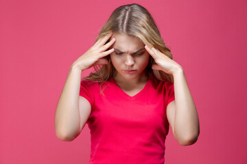 One Beautiful Sad Depressed Caucasian Girl in Pink T-Shirt Suffering From Headache Posing With Both Hands Thinking Against Coral Pink Background.