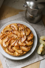 homemade apple pie on the white plate, newspaper background, pie is decorated with caramelized apples, round cake - top view, sweet apple pie with cinnamon, fresh apple, homemade sweets 