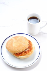 オーストリア発祥のロールパンのカイザーゼンメルにハムカツを挟んだサンドイッチとコーヒーの軽食をとる