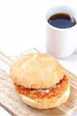 オーストリア発祥のロールパンのカイザーゼンメルにハムカツを挟んだサンドイッチとコーヒーの軽食をとる