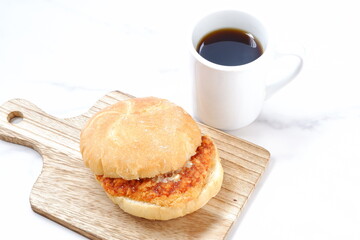 オーストリア発祥のロールパンのカイザーゼンメルにハムカツを挟んだサンドイッチとコーヒーの軽食をとる